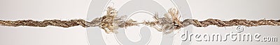Long dirty rope, frayed at both ends and ready to break apart with rope held together by a last strand ready to snap. Concept of Stock Photo