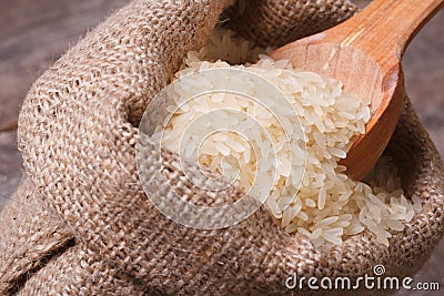 Long dry rice on wooden spoon macro in the sack Stock Photo