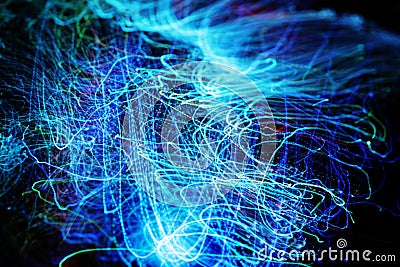 Long exposure of fiber optical light cables in LED neon blue glow. Optics with spiral motion effects for fast data Stock Photo