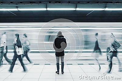 Long exposure picture with lonely man at subway station with blurry moving train and walking people Stock Photo