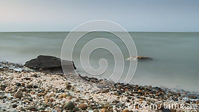 Long exposure seascape. in the foreground stones. Pink sunrise sunset Stock Photo