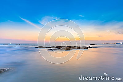 Long exposure shot of calmness sea and the rock in sunset Stock Photo
