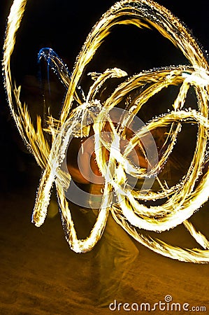 Long exposure shot from a fire juggling act, performed by a man with a red hat, showing the light trail create by the 3 burning Stock Photo