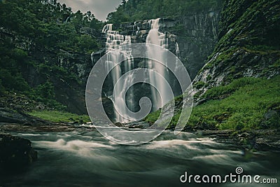 Long exposure shot of a Skjervefossen waterfall in a valley emerging from the forest in Bergen area Stock Photo