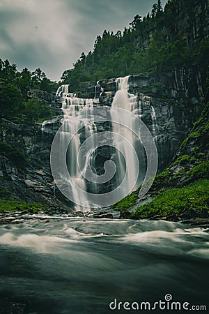 Long exposure shot of a Skjervefossen waterfall in a valley emerging from the forest in Bergen area Stock Photo