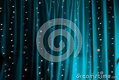 Long exposure of string fairy lights on aqua-blue illuminated curtain Stock Photo