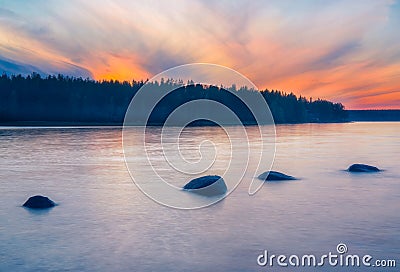 Long Exposure of Sunset at the Paijanne lake. Beautiful scape with stone beach, pine forest and water. Lake Paijanne, Finland Stock Photo