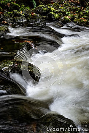 Long exposure vertical shot of a creek flowing through rocks in Sooke, Vancouver Island, BC Canada Stock Photo