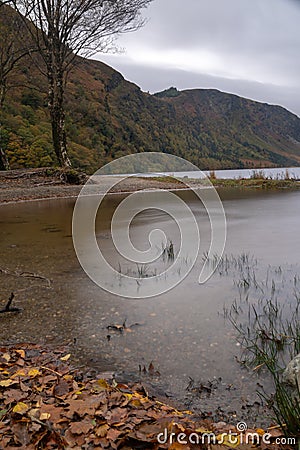 Long exposure view, silky water during autumn in the Wicklow Mountains. Rock on front, Glendalough Upper lake covered with mist an Stock Photo