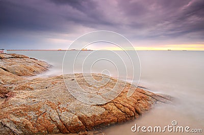 Long exposure of wave hitting rock during twilight with stunning Stock Photo