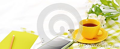 Long Flat lay banner phone, yellow cup of tea and flowers on white blanket with green napkin Stock Photo