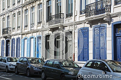 Long french building with blue shutters and row of cars Stock Photo