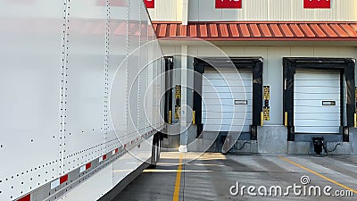 Long, 53 ft semi trailer parked at shipping warehouse docks to pick up or deliver a load. Trucking business concept, shipping and Stock Photo