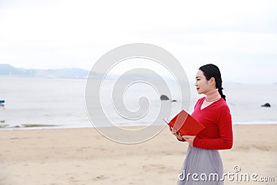 Young asian chinese woman read book walk along Sand Beach Stock Photo
