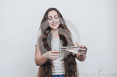 Long-haired girl pours water from bottle into glass Stock Photo