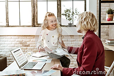 Long-haired pretty girl with wide smile observing articles in beauty magazine Stock Photo