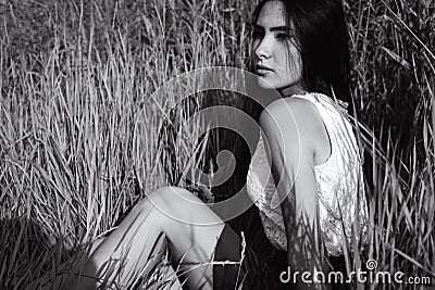 Long-haired teen girl is sitting on grass meadow Stock Photo