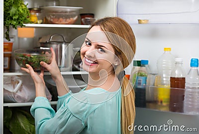 Long-haired woman arranging space in fridge at home Stock Photo