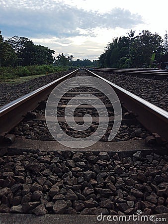 a long iron carriageway, splitting the trees, and under a cloudy sky Stock Photo