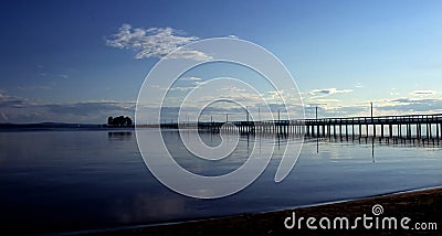 Long jetty in dusk and calm waters Stock Photo