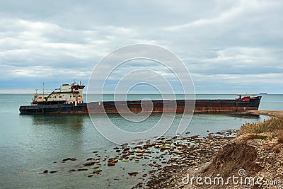 A long old ship wrecked on the Russian coast. The rusty drydocker was nosed against the shore and tilted. Stock Photo