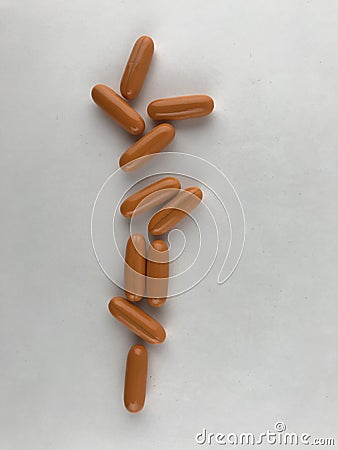 Long orange tablets are arranged on a white background. Stock Photo