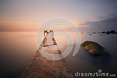 Long pier on beach at sunset Stock Photo