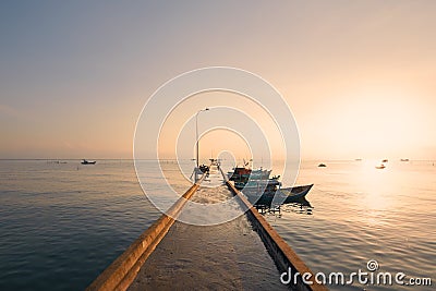 Long pier with moored boats in fishing village at sunrise Stock Photo