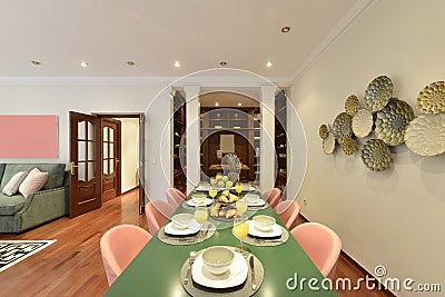 Long plain green dining table with pink velvet upholstered chairs in a living room with sofas and an office with classic wooden Stock Photo