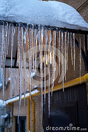 Long pointed backlit icicles on a roof Stock Photo