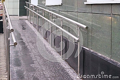 Long ramp. Metal smooth handrails. Building wall Stock Photo