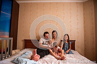 Long range shot of beautiful family on the bed in the morning in the sun from window. General view Stock Photo