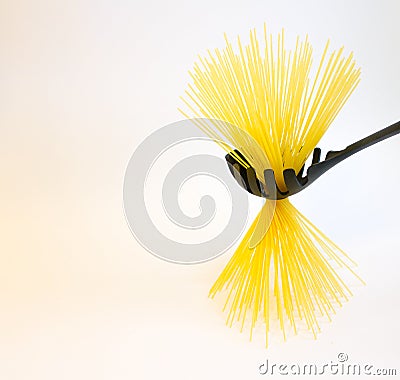 Long raw yellow spaghetti in black plastic spoon isolated on white Stock Photo
