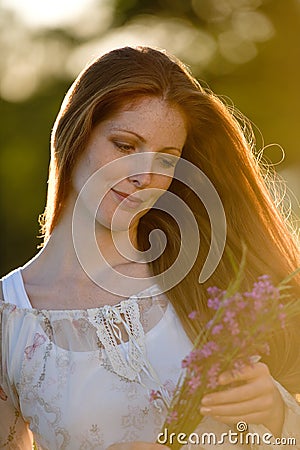 Long red hair woman in romantic sunset meadow Stock Photo