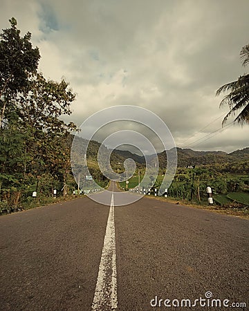 a long road stretches in the middle of village Stock Photo