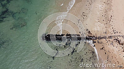 Long, rocky wave breaker on the beach with calm waves crashing against it on a Summer`s day at Point Lonsdale, Mornington Stock Photo