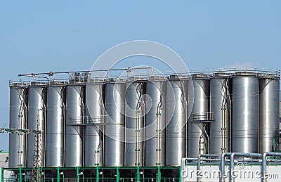 Long row of stainless storage silos for liquids and differents types of free flowing raw materials Stock Photo
