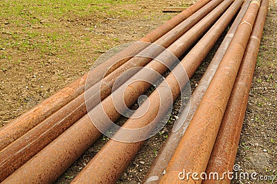 Long rusty pipes in meadow beside construction site Stock Photo