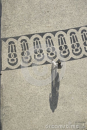 Long shadows of people on a square with pattern of paving stones in Lisbon Editorial Stock Photo