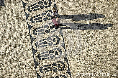 Long shadows of people on a square with pattern of paving stones in Lisbon Editorial Stock Photo