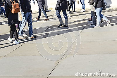 Long shadows of walkers walking on bright concrete slab paving Editorial Stock Photo