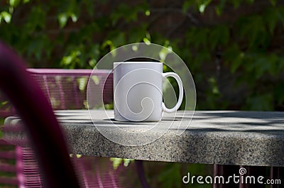 A long solo blank white coffee mug on a park table Stock Photo