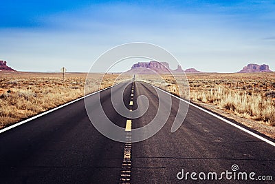 Long straight american road with vanishing point into Monument Valley Stock Photo