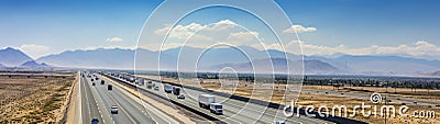 A long and straight stretch of highway with cars and trucks traveling in both directions, surrounded by open landscapes and a Stock Photo