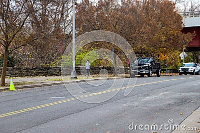 A long street with gorgeous autumn trees along the sidewalk with a person walking on the sidewalk with parked cars on the street Editorial Stock Photo