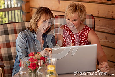 Long time friends senior women laugh together while lookiing at lap top, at home. Two Senior Women Using Laptop at home Stock Photo