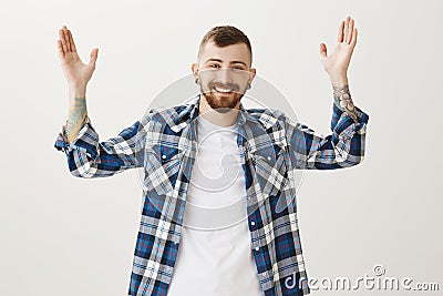 Long time no see. Portrait of friendly relieved young male model with beard and stylish hairstyle, raising palms and Stock Photo