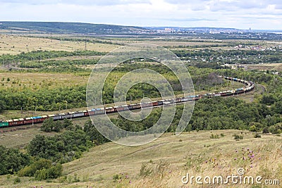 A long train loaded with double-stack cargo containers winds its way around tight s-curves in mountain countryside Stock Photo