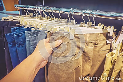 Long trousers or pants jeans clothing for sale discount in store. Man hand check some jeans and choose some item. Stock Photo