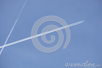 Long white plane traces in the clear cloudless blue sky and big passenger supersonic aircraf with four jet engines flying high Stock Photo